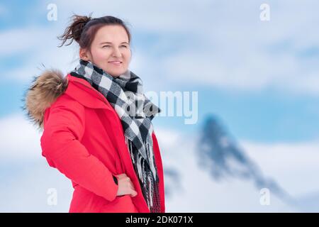 Portrait der Frau Reisende in roten Winter winddichte Jacke, schwarz und weiß Schal um den Hals gekleidet. Geheimnisvolle Frau auf dem Hintergrund der Berge Stockfoto