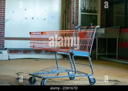 Ein roter Einkaufswagen in einem großen leeren Raum in Ein zerstörtes verlassene Gebäude Stockfoto