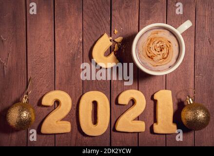 A top view of numbers 2021 made of cookies and a cup of coffee with a notebook on a table - new year concept Stock Photo