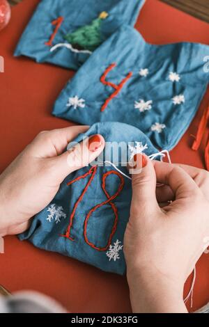 Stoffbeutel für Weihnachtsgeschenke und handgefertigte Zahlen mit Dekorationen auf dem Tisch. Handgemachtes Adventskalender für Weihnachten Stockfoto