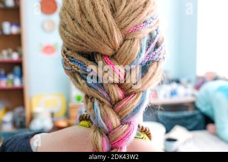 Farbiges Zopf auf dem hellen Kopf des Mädchens. Rückansicht. Die Bänder sind zu Dreadlocks geflochten Stockfoto