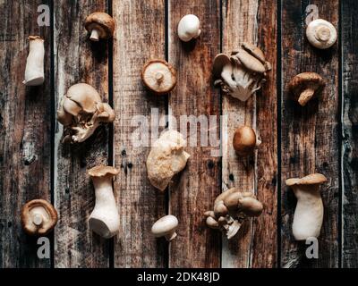 Set von ausgewählten Pilzen auf alten rustikalen Holzhintergrund. Draufsicht oder flaches Lay von Shiitake, Austernpilz, Pom Pom, Champignon Pilze. Muster aus verschiedenen Arten von asiatischen Pilzen. Stockfoto