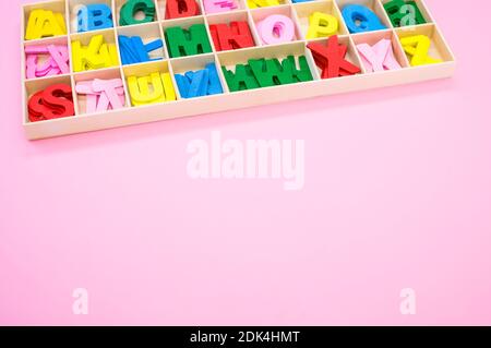 Ein hoher Winkel von bunten Holzbuchstaben in ihrem Fall, auf einer rosa Oberfläche platziert Stockfoto