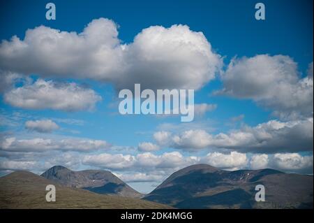 A beautiful landscape of the mountains gleaming under the fluffy cloudy blue sky Stockfoto