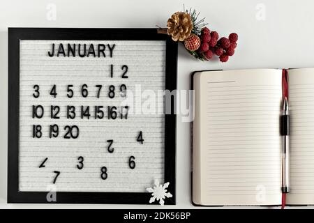 Notizblock für Notizen zu Zielen und Plänen für das neue Jahr, Kalender und Weihnachtsbaumschmuck auf dem Desktop Stockfoto