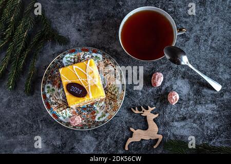 Neujahrsfoto eines Kuchens mit Tee, getrockneter Kumquat auf einem Tisch mit Tannenzweigen und Spielzeug, Postkarte. Stockfoto