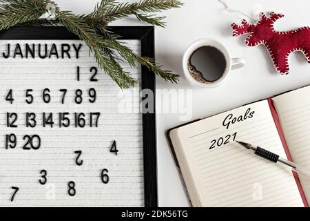 Notizblock für Notizen von Zielen und Plänen für das neue Jahr, Kalender, eine Tasse Kaffee, Weihnachtsbaumschmuck auf dem Desktop. Inschrift in engl Stockfoto