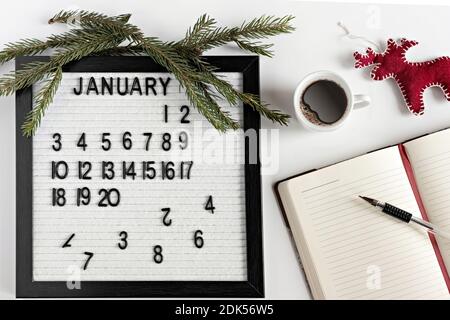 Notizblock für Notizen von Zielen und Plänen für das neue Jahr, Kalender, eine Tasse Kaffee, Weihnachtsbaumschmuck auf dem Desktop Stockfoto