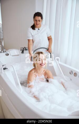 Wunderschöne junge Frau, die sich in einer Hydromassage-Badewanne entspannen kann Ein Wellness-Center Stockfoto
