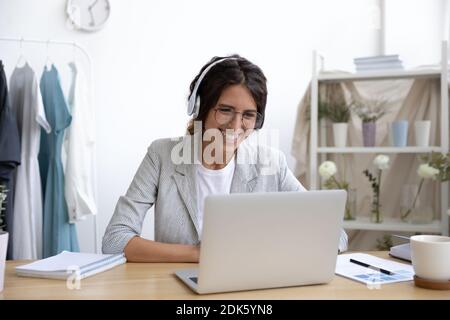 Fähige Designerin, die von zu Hause aus mit einem Laptop in Kopfhörern arbeitet Stockfoto