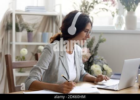 Aufmerksame Frau mit Kopfhörern Telearbeiter, die an Online-Briefing teilnehmen Stockfoto