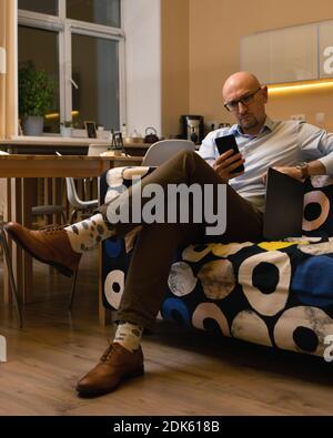 Business erwachsenen Mann mit Brille runzelt beim Lesen Nachricht oder schlechte Nachrichten auf seinem Handy. Home Office Stockfoto