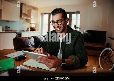 Lächelnd gemischte Rennen Geschäftsmann Gesicht Timing Familie von digitalen Tablet Am Schreibtisch sitzen und sich wohl fühlen Stockfoto
