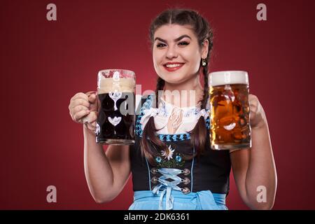 Junge deutsche Mädchen in Tracht mit zwei Pinten Bier, braun und blass Stockfoto