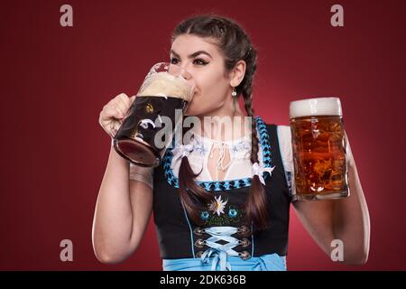 Junge deutsche Mädchen in Tracht mit zwei Pinten Bier, braun und blass Stockfoto