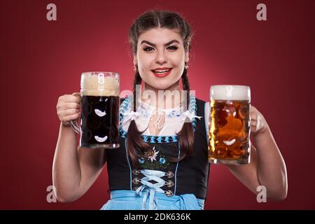 Junge deutsche Mädchen in Tracht mit zwei Pinten Bier, braun und blass Stockfoto