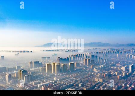 Die Advektionswolken fließen langsam zwischen den städtischen Gebäuden, wie ein Märchenland in Shijiazhuang Stadt, nördlich Chinas Provinz Hebei, 12. Dezember Stockfoto