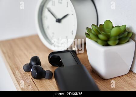 Schnurlose Ohrhörer im Regal mit Wecker und Hausanlage. Kopfhörer im Home-Office-Innenraum Stockfoto