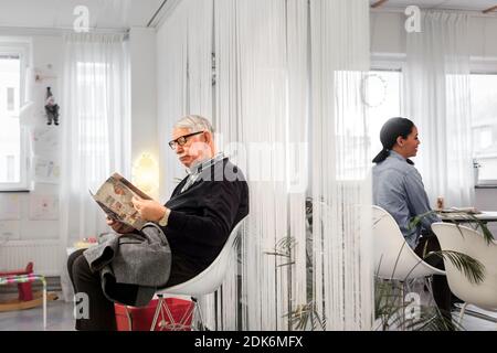 Mann liest Magazin im Warteraum Stockfoto