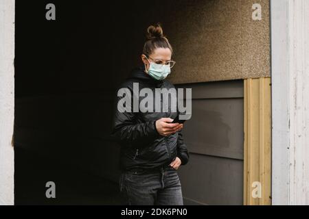 Frau trägt Gesichtsmaske mit Handy Stockfoto