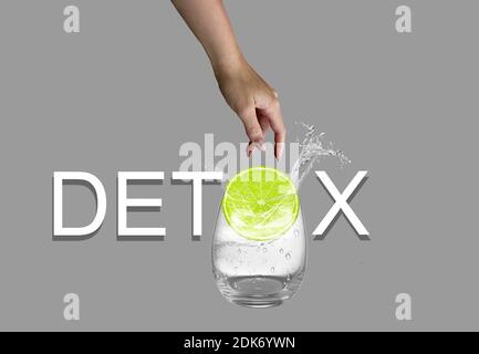 Weißer Detox-Text auf grauem Hintergrund isoliert. Weibliche Hand werfen Stück Zitrone zu Glas Wasser. Stockfoto