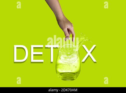 Weißer Detox-Text auf grünem Hintergrund isoliert. Weibliche Hand werfen Stück Zitrone zu Glas Wasser. Stockfoto