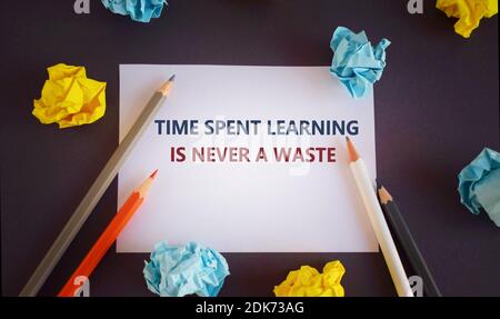 Handwriting text writing Time Spent Learning Is Never A Waste.. Concept meaning Education has no end Keep the wisdom.Pencils and paper lobs on dark ba Stock Photo