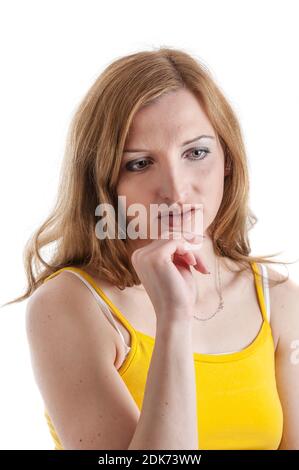 Kopf- und Schulterportrait einer zurückgezogenen jungen Frau mit verbeugten Augen, die ihre linke Hand vor weißem Hintergrund an ihre Wange hält. Stockfoto