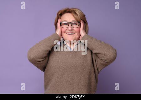 Wow. Reife Frau, die aufgeregt die Hände auf dem Kopf hält. Schockiert überrascht überrascht verblüfft. Positive menschliche Emotionen Stockfoto