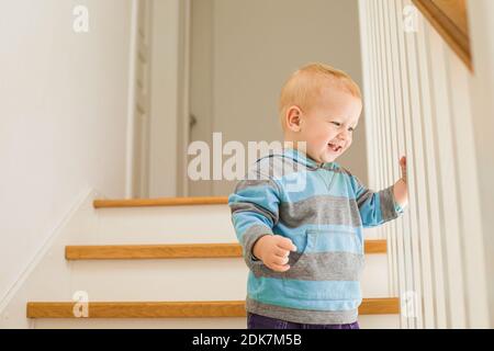 Fröhlicher Junge lächelnd auf Holztreppe stehend Stockfoto