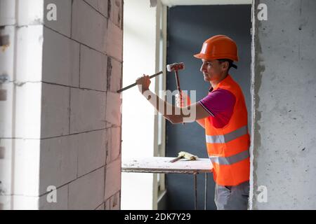 Junger Arbeiter, der einen Hammer und einen spitzen Meißel hält Stockfoto