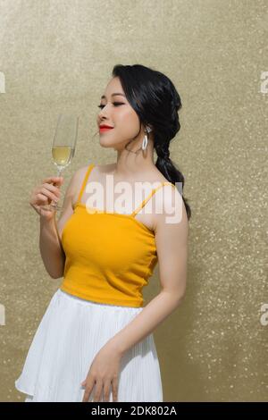 Party, Getränke, Urlaub, Luxus und Feier Konzept - lächelnde Frau in Abendkleid mit einem Glas Sekt auf Gold Hintergrund. Stockfoto