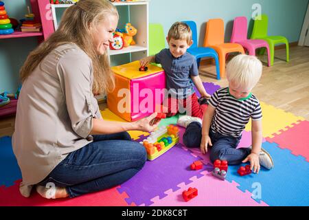 Die Erzieherin bildet mit kleinen Jungen einen Konstrukteur Stockfoto