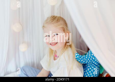 Lächelndes Mädchen sitzt auf Bett Stockfoto