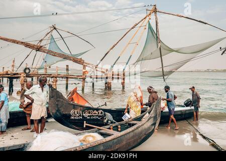 Nicht identifizierte Fischer stehen neben ihren Booten neben chinesischen Fischernetzen in Fort Kochi, kerala indien Stockfoto