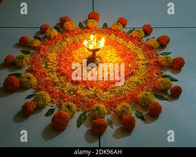 Onam Pookalam/Blumenteppich mit brennenden Messingöllampen - Onam Festival/Kerala/Indien Stockfoto