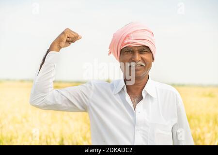 Indian Farmer steht vor Ackerland und zeigt Stärke Geste - Konzept zeigen von landwirtschaftlichen Ackerland ist Bauern Stärke. Stockfoto