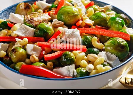 Makkaroni-Salat mit Brokkoli-Sprossen, Paprika-Streifen, Feta und Erdnuss in einer Schüssel, horizontale Ansicht von oben, Nahaufnahme Stockfoto