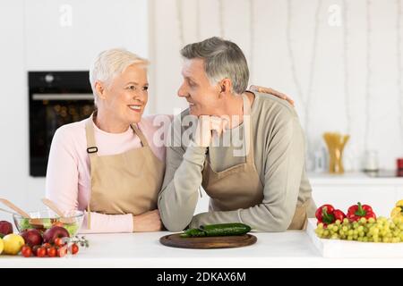 Ältere Ehepartner Umarmen Vorbereitung Abendessen Stehend In Der Modernen Küche Stockfoto