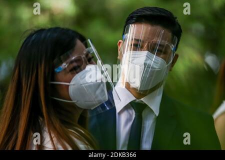 Makati, Philippinen. Dezember 2020. Ein Paar, das Gesichtsmasken trägt, wird während einer maskierten Hochzeit in einem Park in Makati City, Philippinen, am 15. Dezember 2020 gesehen. Die philippinische Regierung hat eine strengere Politik der Gesichtsbedeckung auferlegt, da sie Bedenken wegen einer möglichen Erhöhung in Fällen während der Ferienzeit hat. Quelle: Rouelle Umali/Xinhua/Alamy Live News Stockfoto