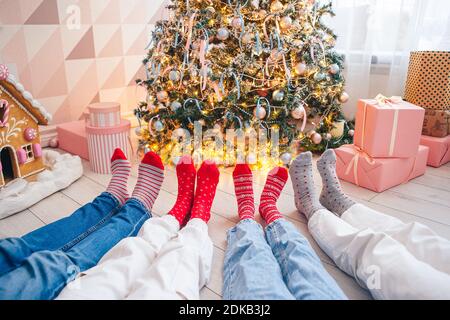 Nahaufnahme von Familienfüßen in Wollsocken vorbei Der weihnachtsbaum Stockfoto