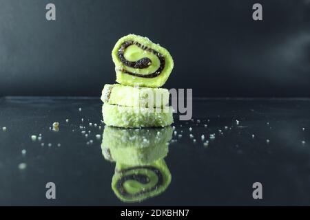 Drei Pastillen aus Marmeladenrot und Zitrone gleiten auf einem schwarz-glasig verspiegelten Hintergrund mit einem freien Raum mit einer Kopie des Raumes. Stockfoto