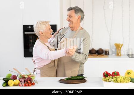 Ältere Ehepartner Tanzen In Der Modernen Küche Zu Hause Am Wochenende Stockfoto