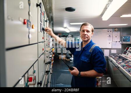 Marine Engineer Officer Steuerung von Schiffsmotoren und Antrieb in Motor Kontrollraum Stockfoto