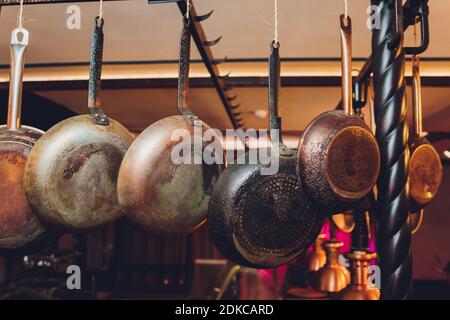 Alte Küchenpfannen hängen an der Bar. Verschiedene Größe der Pfannen an der Wand, Dekoration, Küche Hintergrund Stockfoto