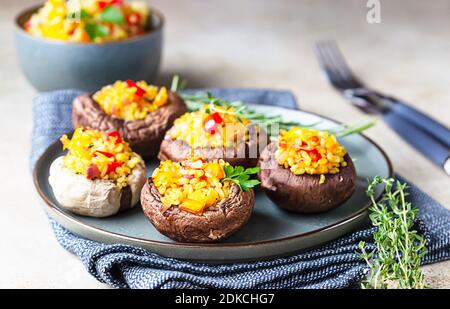 Gefüllte portobello-Pilze mit Bulgur, Gemüse und aromatischen Kräutern auf betontem Hintergrund. Vegetarisches Essen. Selektiver Fokus. Stockfoto