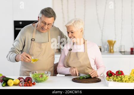 Glückliches Senior-Paar Macht Salat Zusammen In Der Küche Zu Hause Stockfoto
