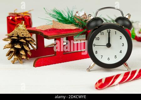 santa claus Schlitten, Wecker, santa claus Stab, goldenen weihnachtsbaum Kegel und Boxen mit Geschenken auf weißem Holz Hintergrund mit goldenen Adern Stockfoto