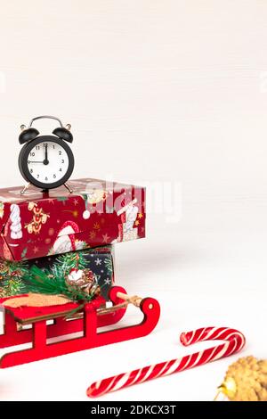 santa claus Schlitten, Wecker, santa claus Stab, goldenen weihnachtsbaum Kegel und Boxen mit Geschenken auf weißem Holz Hintergrund mit goldenen Adern Stockfoto