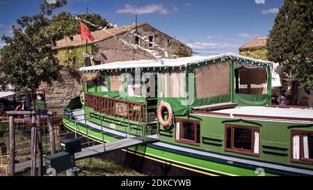 Die Péniche Tamata wurde 1924 erbaut. Das Boot ist 24 Meter lang und wurde in ein Lebensmittelgeschäft umgewandelt. Es befindet sich am Canal du Midi in Le Somail. Der Kanal ist ein UNESCO-Weltkulturerbe und wurde 1681 fertiggestellt. Es wurde von Pierre Paul Riquet entworfen. Stockfoto